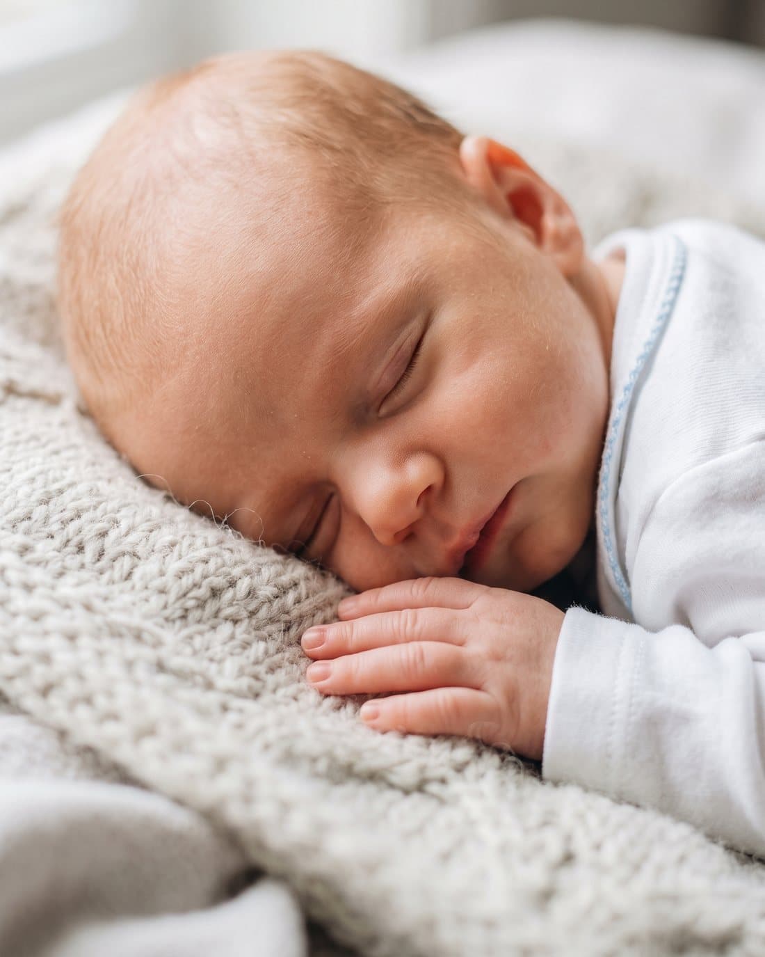 Recém-nascido dormindo tranquilo sobre uma manta, com a mãozinha relaxada — o sono profundo que o Método das 3 Noites busca